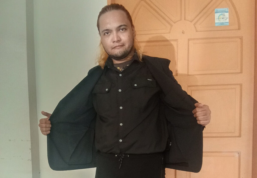 Filipino Male Model holding Uniqlo Miracle Air Jacket open with two hands exposing top underlay garment.