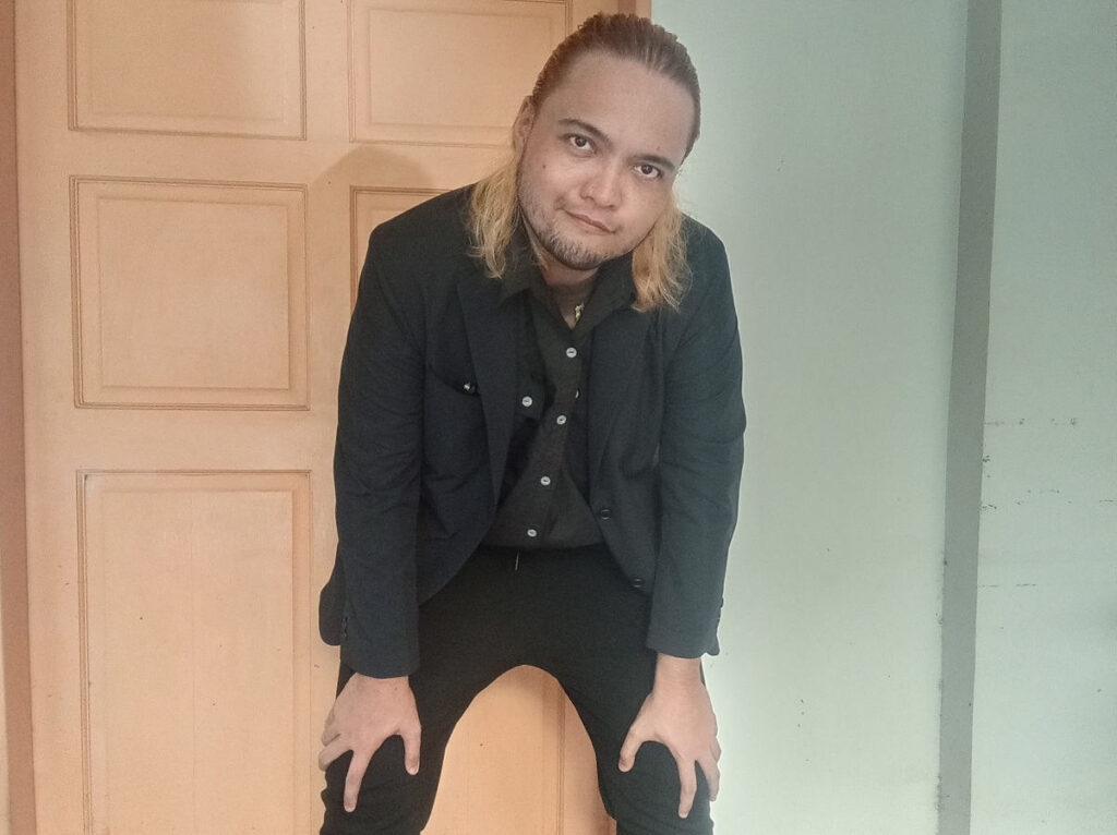 Filipino Male model in business casual wearing Uniqlo Miracle Air Jacket while leaning back on the door
